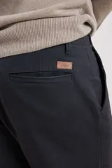 Pantalón chino de hombre color verde oscuro, corte slim, confeccionado en algodón con elastano, con triple pespunte en las costuras y botones al tono.