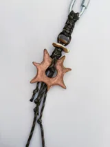 Charm para bolso o accesorios con mosquetón metálico, tejido de macramé en cordón negro y dijes de cerámica esmaltada en tonos violeta y celeste.