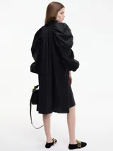 Vestido camisero blanco con botones frontales, cuello camisero, manga larga abullonada con puños ajustables y corte a la rodilla.