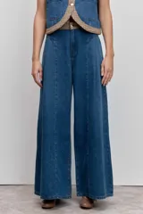 Pantalón de jean azul de corte ancho y tiro alto, con costuras verticales frontales que estilizan la silueta y diseño de pierna recta.