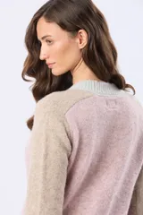Buzo tejido de punto con diseño de bloques de color en tonos rosa, beige y gris. Presenta cuello redondo, mangas largas y puños acanalados.