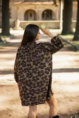 Vestido corto de lino con estampado floral en tonos tierra, verde y marrón. Presenta cuello redondo, mangas tres cuartos con volumen y silueta holgada.