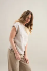 Blusa de silueta amplia y relajada, confeccionada en lino con cuello redondo, mangas cortas y recorte diagonal en el frente.