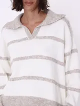 Sweater de punto color blanco con rayas horizontales color beige, con cuello polo y escote en V.