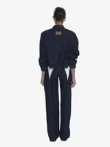 Chaqueta de denim color negro lavado, de calce regular y textura suave. Presenta cuello camisero, cierre frontal y mangas largas con puños ajustados con elástico.