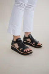 Sandalias negras de cuero con plataforma y tiras anchas.