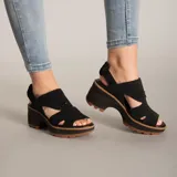 Sandalia de plataforma color negro, confeccionada en gamuza con diseño de aberturas laterales y cierre de tira con hebilla en el talón. Cuenta con una suela de goma dentada en color marrón y entresuela de EVA.