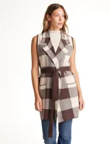 Chaleco tejido largo de la marca Absolutely Famous, con estampado a cuadros en tonos marrón, beige y blanco. Presenta cuello con solapa, abertura central, bolsillos aplicados en la parte delantera, pasadores en la cintura con lazo de ajuste y un tajo central en el ruedo trasero.