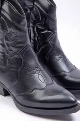 Bota texana de cuero sintético color marrón, con punta fina, taco bajo y costuras decorativas tradicionales en la caña.