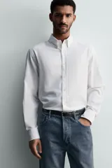 Camisa de corte regular fit confeccionada en tejido de algodón con efecto lavado. Presenta cuello abotonado, manga larga con puños abotonados, bolsillo en el pecho y cierre frontal con botones.