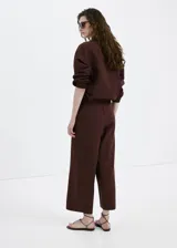 Pantalón marrón de corte recto y tiro medio, confeccionado en mezcla de lino, viscosa y algodón. Cuenta con diseño largo y cintura elástica.