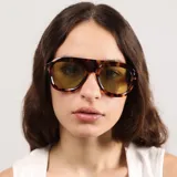 Lentes de sol con marco de acetato negro y diseño de puente plano, estilo aviador moderno con cristales oscuros.