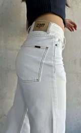 Pantalón jean de tiro alto color blanco, corte recto y pierna ancha.