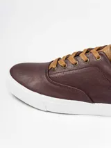 Champion de estilo urbano en color azul marino, con detalles en cuero sintético color suela en la lengüeta y el talón. Presenta perforaciones decorativas en los laterales y suela de goma blanca.