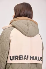 Campera acolchada reversible con capucha, diseño de matelassé, cierre frontal y puños elásticos. Presenta un lado en color verde oliva y otro en color beige.