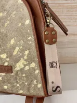 Mochila de cuero marrón con estampado animal print dorado y detalles en cuero liso. Cuenta con cierre superior, asa de mano y correas ajustables para los hombros.