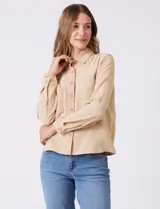 Camisa de crepe color beige con cuello clásico, cierre frontal con botones y dos bolsillos aplicados en el pecho.