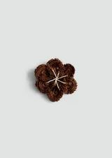 Broche en forma de flor de gran tamaño, confeccionado en tejido de crochet color marrón, con detalle central de pistilos en hilo blanco y naranja.