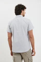 Camisa de manga corta a rayas verticales blancas y celestes, con cuello abotonado y bolsillo en el pecho.