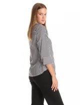 Camisa de corte clásico con estampado de rayas verticales en blanco y negro. Presenta cuello con solapa, escote en V, cierre frontal con botones perlados y apliques de perlas decorativas en la parte superior delantera. Posee mangas tres cuartos con puños abotonados.