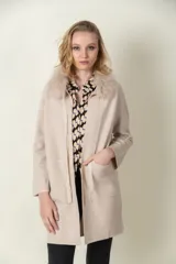 Saco largo color beige con cuello de piel sintética, solapas y bolsillos delanteros.