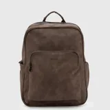 Mochila urbana de diseño minimalista en color marrón, confeccionada en material sintético con acabado mate. Cuenta con un compartimento principal amplio con cierre, un bolsillo frontal con cierre y logo grabado, y bolsillos laterales elásticos.