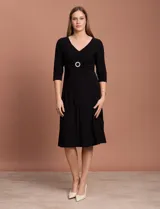 Vestido midi negro de RM Richards en seda fría, con escote en V, mangas 3/4, frunce en la delantera y aplique circular de brillos en el centro.