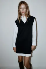 Vestido corto que combina una camisa blanca de manga larga con cuello solapa y botones frontales, con un chaleco de tejido negro de punto con escote en V.