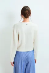 Sweater de punto gris con diseño de corazón blanco en el pecho, cuello redondo y mangas largas.