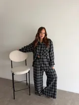 Camisa de viyela con estampado de cuadros en tonos marrones, beige y negro. Presenta cuello clásico, cierre frontal con botones, mangas largas con puños abotonados y dos bolsillos delanteros con solapa.