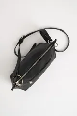 Bolso bandolera negro de cuero sintético con correa fina ajustable.