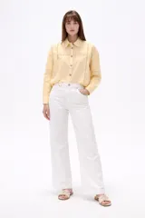 Camisa de algodón color blanco, de corte holgado y manga larga. Presenta detalles de encaje tipo puntilla en el frente, espalda y mangas, con cierre frontal de botones y cuello camisero clásico.