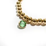Pulsera elástica con cuentas doradas y dije colgante de cristal facetado color verde esmeralda.