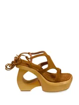 Sandalias de cuero color marrón con plataforma de madera y tiras de cuero con cordones para atar al tobillo.