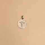 Dije redondo de plata 925 con el símbolo de la medicina.