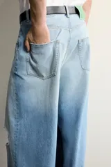 Jeans de corte baggy fit confeccionados en denim de algodón rígido, con tiro medio y diseño de cinco bolsillos. Presentan un lavado claro con efecto desgastado y roturas en las rodillas.