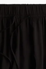 Pantalón de viscosa liviana color negro, de tiro alto y corte amplio, con elástico y cordón ajustable en la cintura.