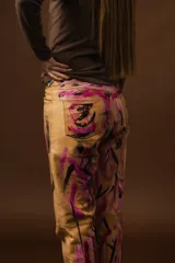 Pantalón de cuero color negro con estampado artístico en fucsia y blanco.