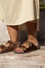 Sandalias bajas con estampado de leopardo, dos tiras con hebillas doradas ajustables y suela plana.