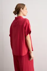 Camisa de manga corta color rojo, de corte holgado, con cuello camisero clásico y cierre frontal abotonado.