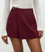 Short pollera de sastrería confeccionado en crepé, con diseño de frente traspasado, cintura alta estructurada y detalle de hebilla metálica lateral.