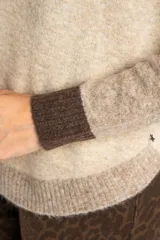 Sweater de punto con diseño color block en tonos beige, marrón y bordó, de cuello redondo y manga larga con puños acanalados en contraste.