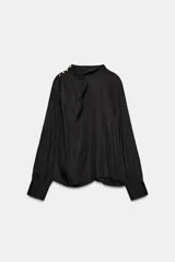 Blusa de tejido satinado con efecto arrugado, de corte holgado y manga larga. Presenta cuello subido y detalle de botones dorados decorativos en uno de los hombros.