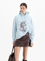Buzo tipo hoodie color celeste, con capucha y cordones ajustables. Presenta una estampa frontal con diseño de auto con esquíes y copos de nieve, además de un logo bordado en la manga.