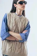 Chaleco de punto color marrón con diseño de ochos, cuello redondo y lazos laterales ajustables.