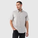 Camisa de manga corta con cuello clásico, cierre frontal de botones y un bolsillo en el pecho. Presenta un diseño de corte regular con textura natural.