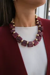 Collar de diseño llamativo compuesto por piezas geométricas de resina en tono rojizo veteado, intercaladas con separadores metálicos dorados de textura acanalada.