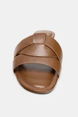 Sandalias planas de piel color marrón, con diseño de tiras cruzadas en la parte delantera y suela baja.