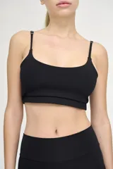 Top deportivo negro con tirantes finos regulables y banda elástica bajo el busto.