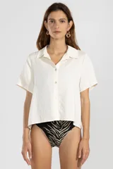 Camisa color crema de lino y tencel, de manga corta, con cuello camisero y cierre abotonado al frente.